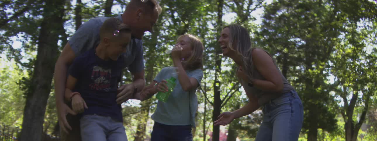 Family enjoys outdoors while the child blows soap bubbles