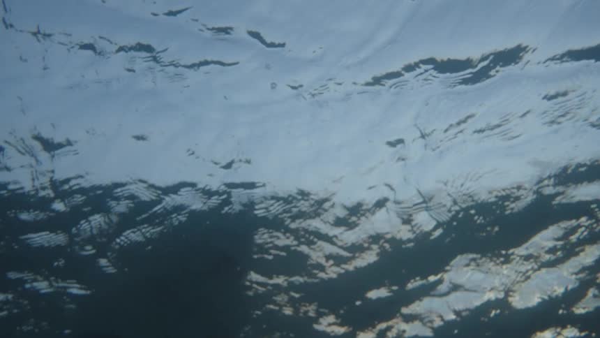 Deep dark ocean waves seen from underwater with shimmering reflections
