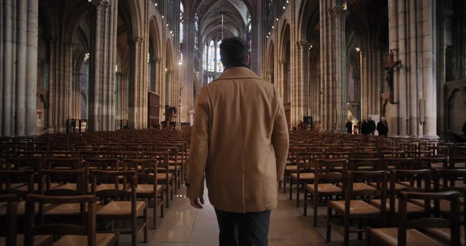 A man walking through the aisle in a cathedral building during daytime