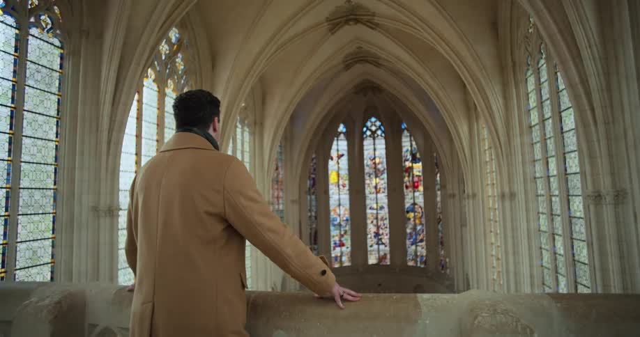 Man stands in the balcony of a church and looks around