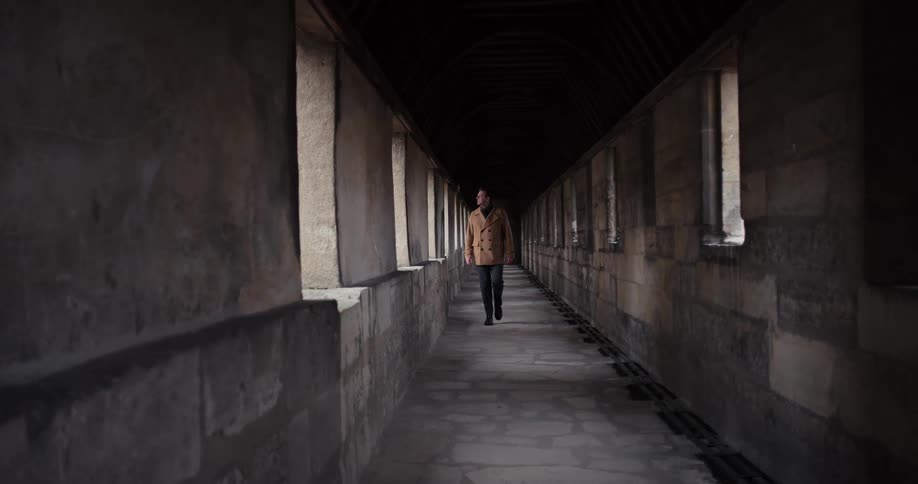 A man walks through a dark stone corridor inside a fortress