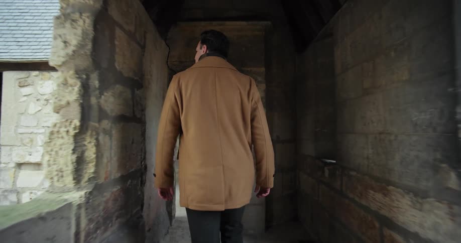 Man walks through a stone corridor walkway inside an old fortress