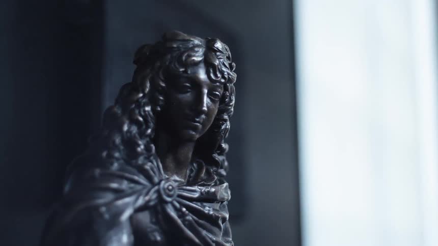 A statue is of a person in the dark room