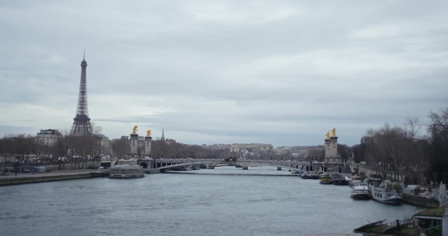 Pedestrians move across a bridge located near the eiffel tower on an overcast winter day
