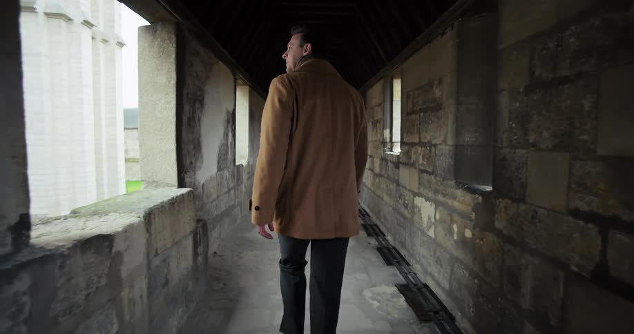 Man walks along a narrow corridor while touring a historic building on a winter day