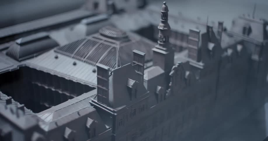 The video is a slightly blurred closeup shot of a large gray architectural model of a european city the model features detailed facades rooftops and windows of historic buildings suggesting a scale replica of a major urban area