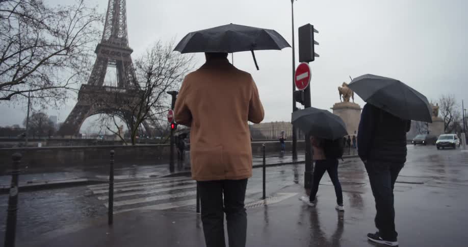 Pedestrians cross a street towards the eiffel tower on a rainy winter day