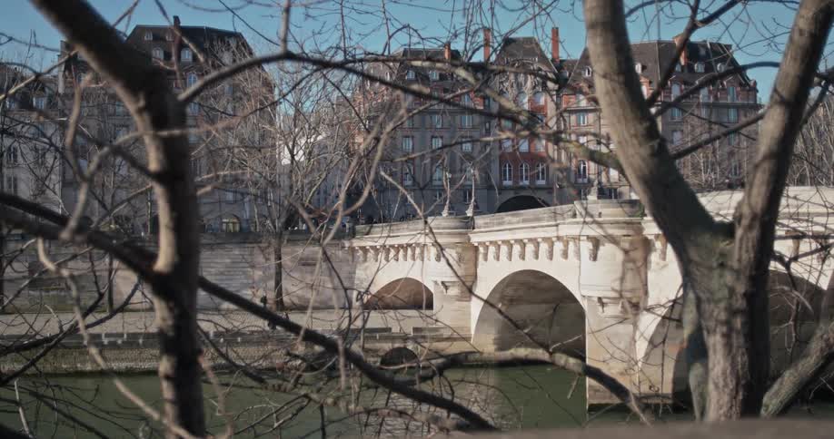 A stone bridge over a river in a european city with bare trees