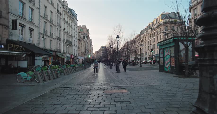 Historic city street with pedestrians walking along buildings on a sunny day