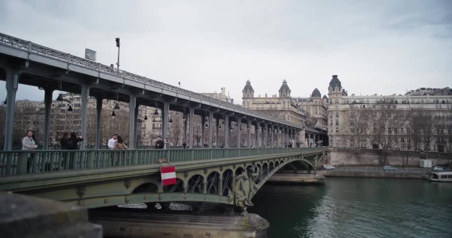Metal bridge spans the river in front of historic buildings