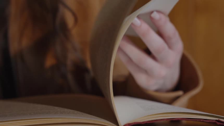 Person flips through the pages of a book in a cozy setting