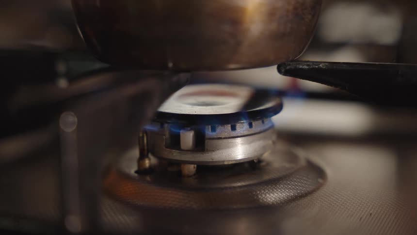 Blue flame heats a pot on the stove