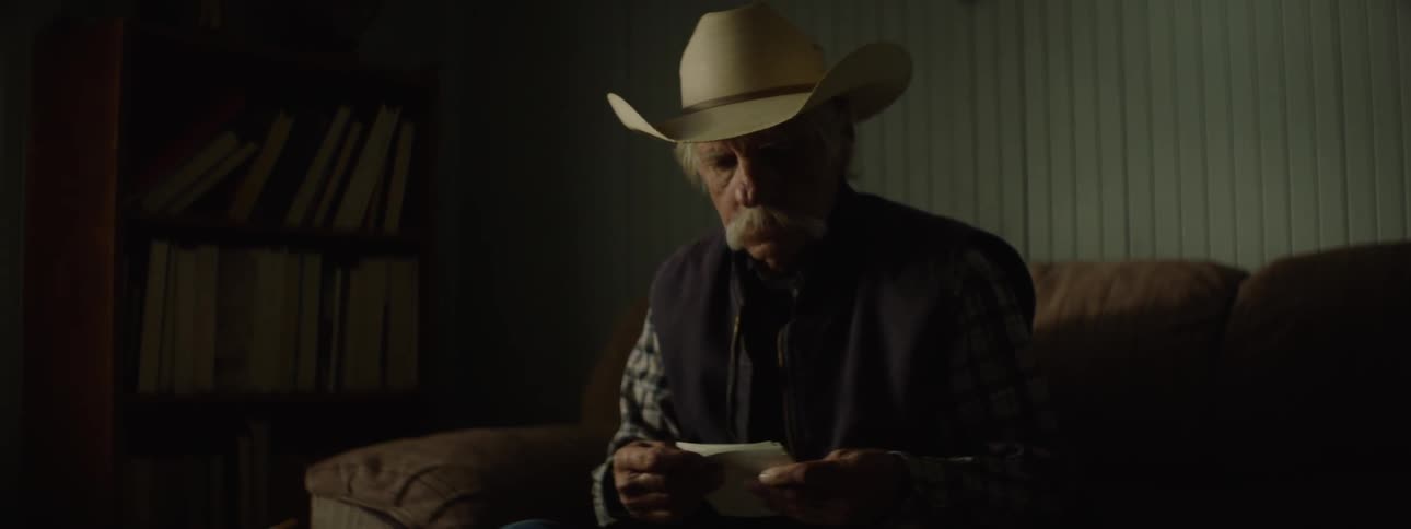 A man is sitting on a bed looking at letters or pictures