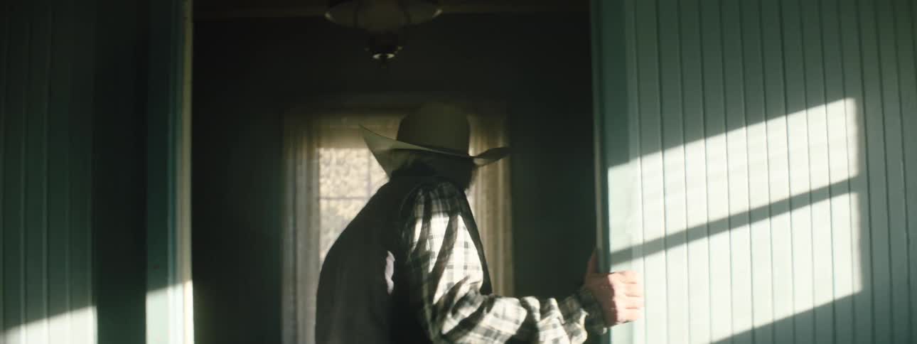 A man in a hat looks around a house with a worried look