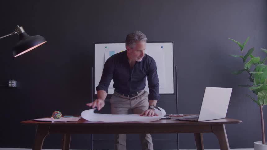 A man lays out a paper on a desk