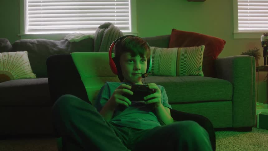 The child sits in the living room playing video games