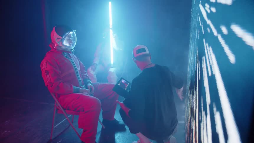 Person in red spacesuit takes part in audiovisual production alongside