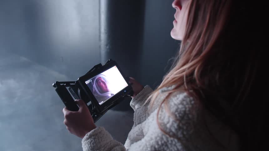 Close up of a female filmmaker viewing media content on a camera screen while on set indoors