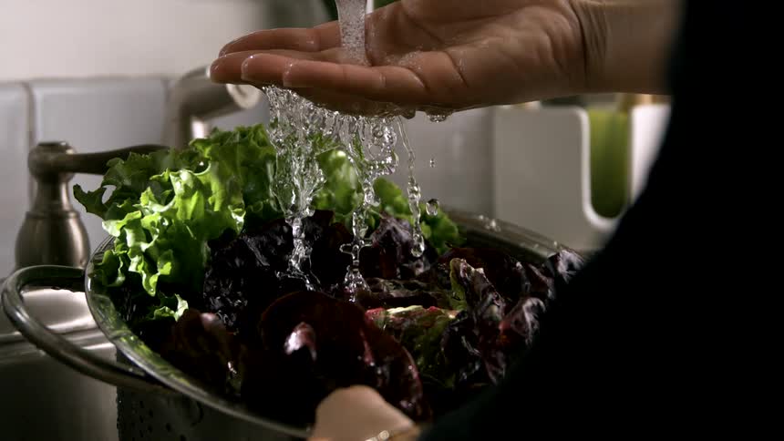 The person is cleaning lettuce in the sink