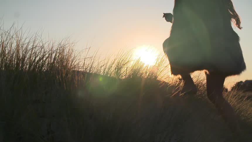 Woman traveling over a grassy field at sunset