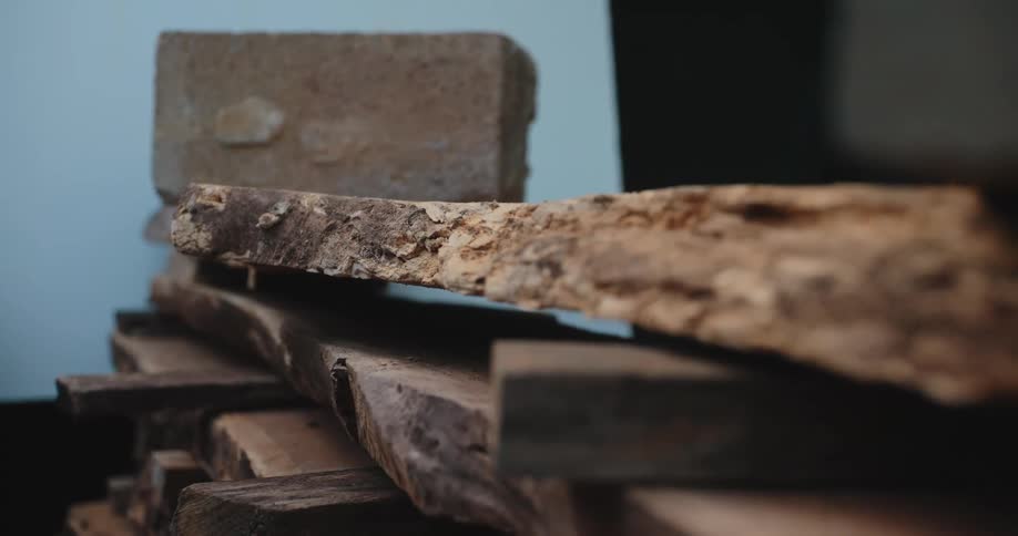 Stacked rough wooden planks with concrete block on dark surface