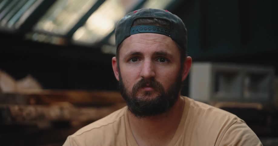 Man wearing a backward cap watches silently