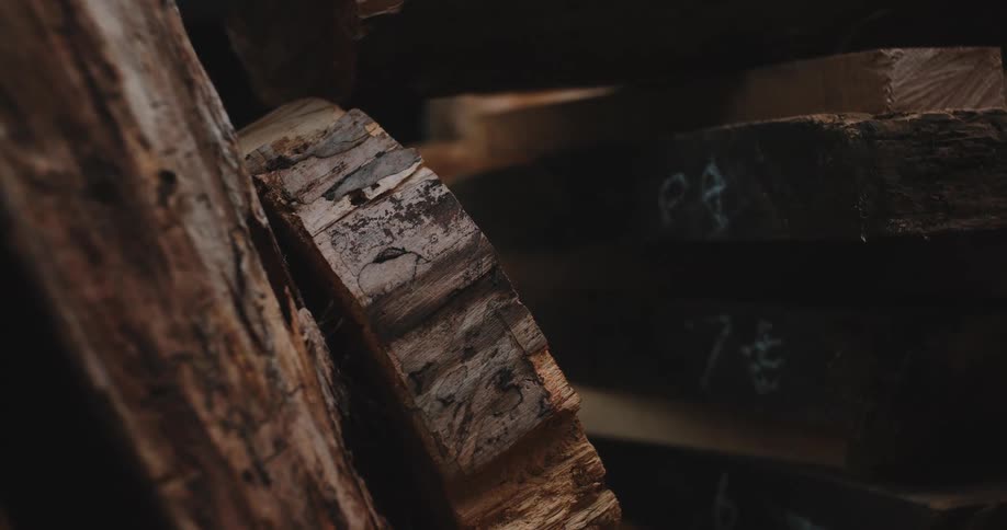 Slices of a tree with the bark still attached lean next to a stack of marked boards