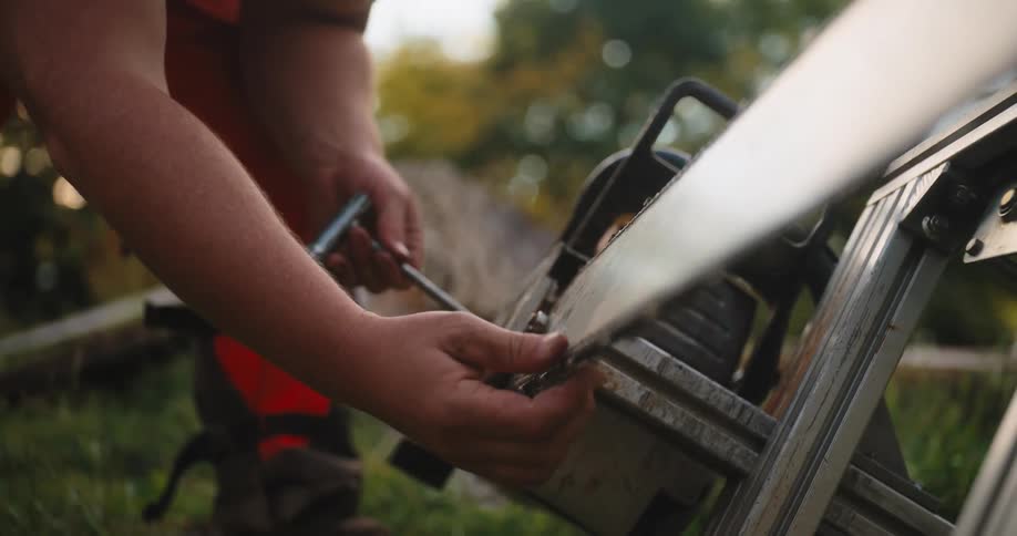 Worker adjusts the chain of a chainsaw outdoors