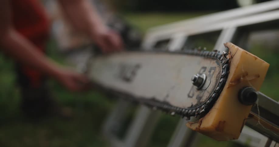 Worker adjusts the chain of a saw on a metal frame