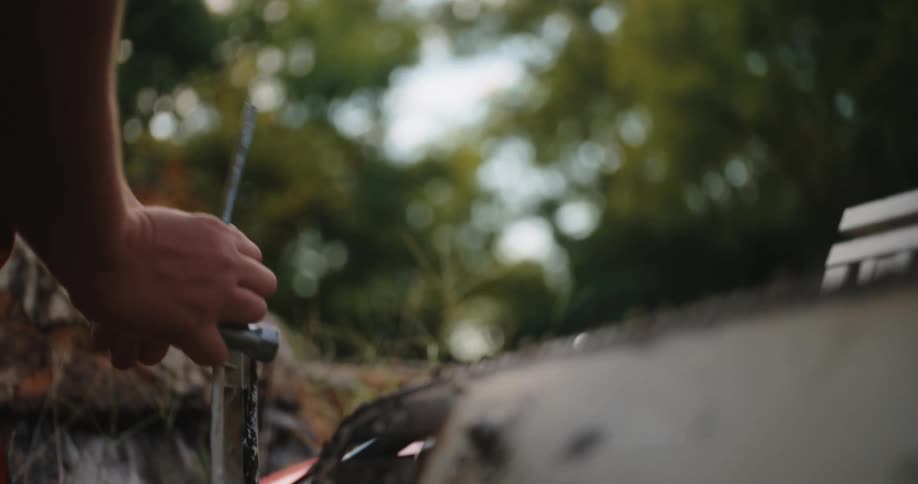 The video is a closeup shot of a mans bearded face as he works wearing a baseball cap and ear defenders he is looking down intently at the task at hand with the scene having a soft natural outdoor lighting