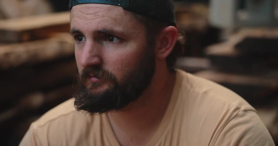 Bearded man wearing a cap looks attentively at something offscreen