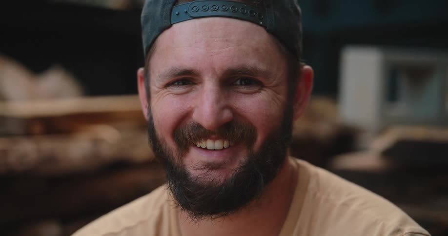 Man wearing a cap smiles in his work environment