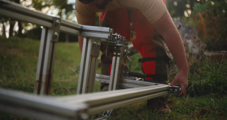 Man adjusts a metal cutting frame in an outdoor area