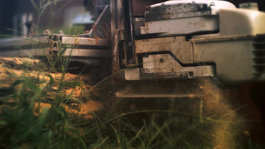 Machine running in a field during the daytime emits a lot of sawdust