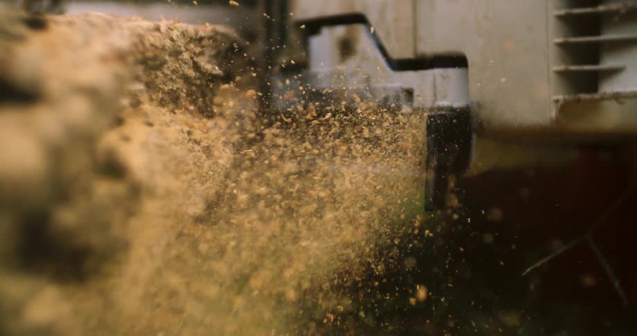 Running chainsaw scatters clouds of sawdust