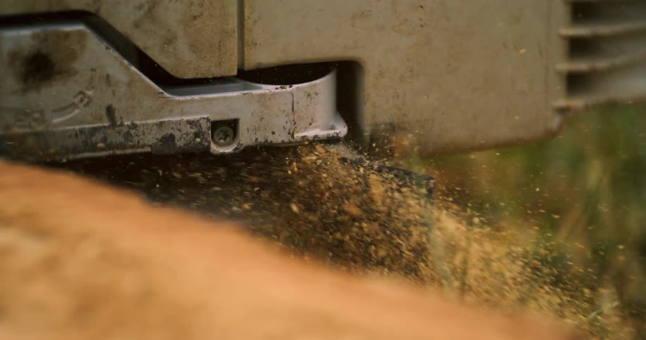 Chainsaw cuts through wood releasing sawdust into the air