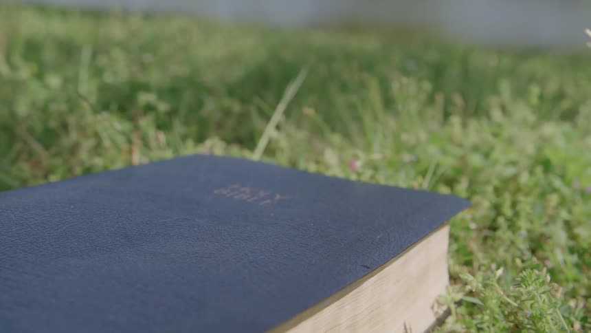 Close up of a bible placed on a field outdoors during daytime