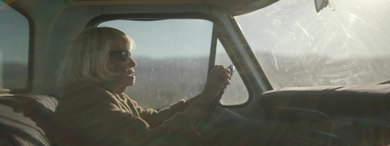 An elderly woman drives an old pickup truck
