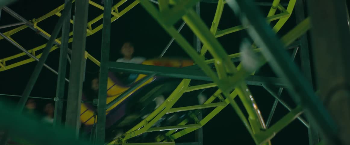 A group of people having fun on a ride in an amusement park at night