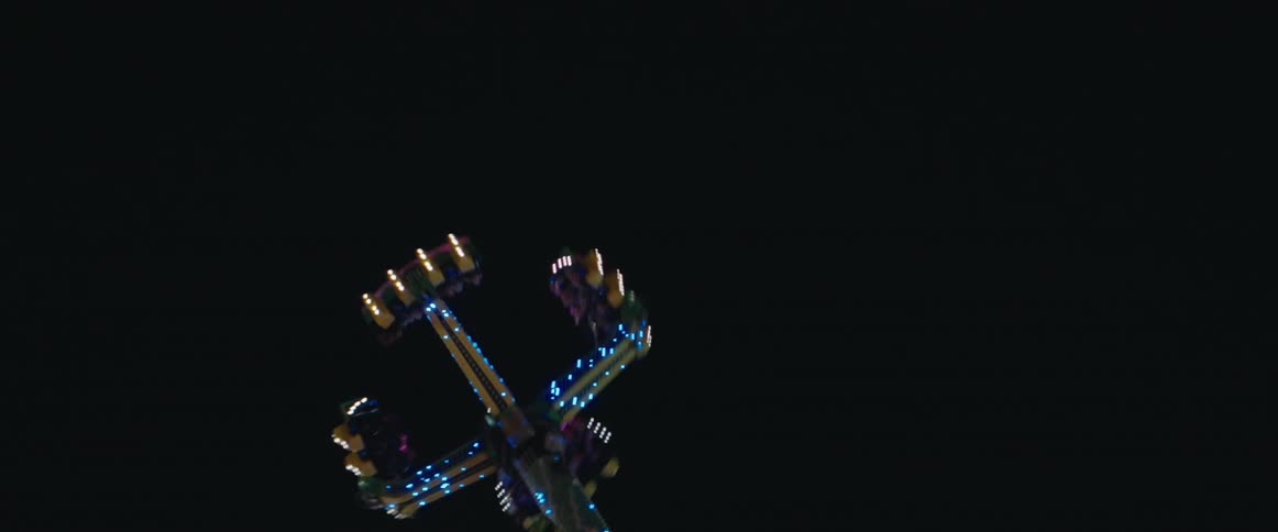 People enjoy an amusement park ride as it turns in midair at night