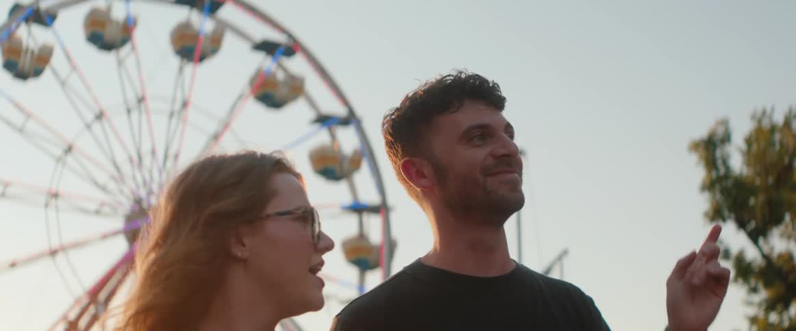 The couple walk and talk at the amusement park