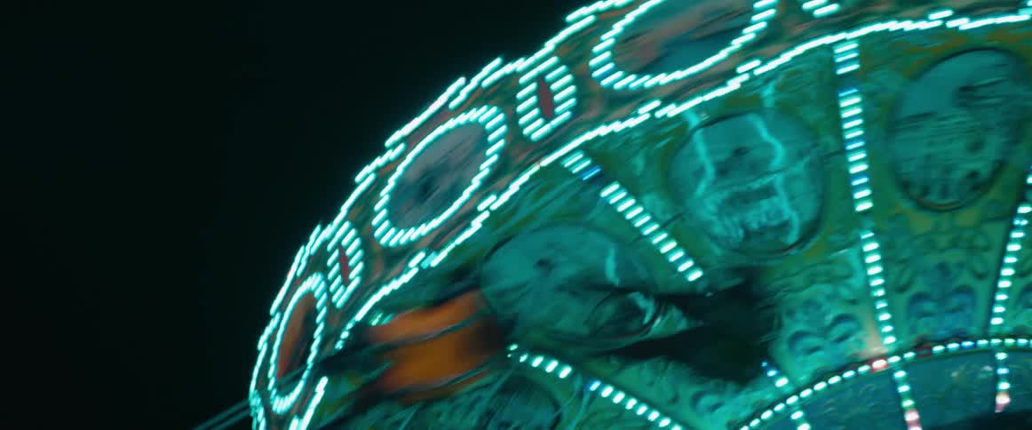 Glowing swing chairs spin on a night carousel