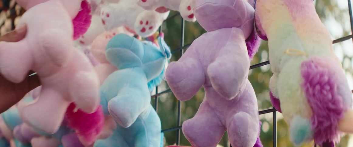 Hand selects a colorful stuffed bear at a fair booth