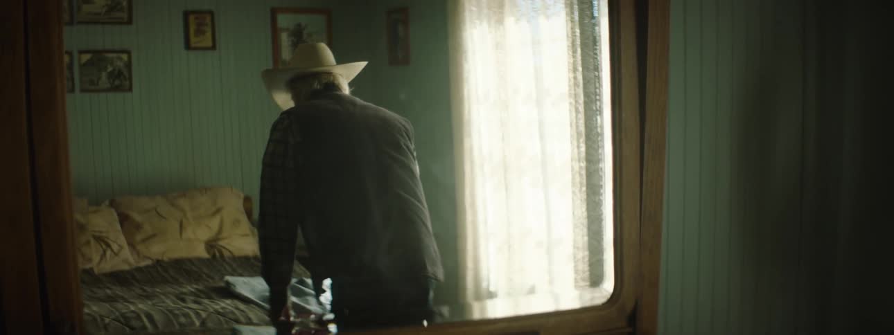 Elderly man puts clothes on a bed