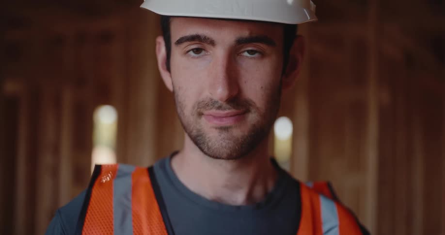 Close up portrait of a young male construction worker standing in a building under construction during daytime