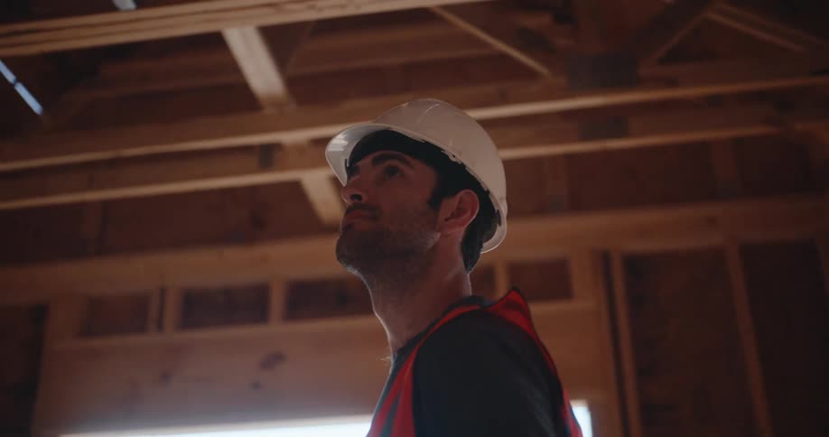 Engineer wearing a helmet observes the wooden framework during inspection