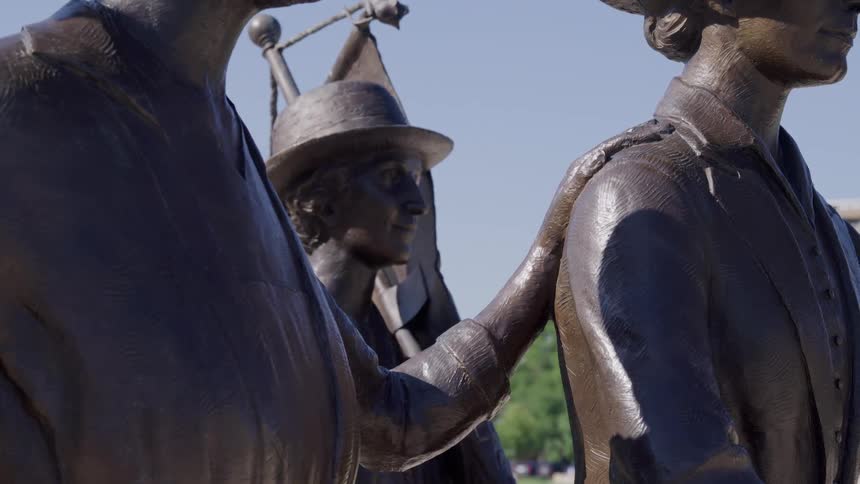 Close up of three lifelike sculptures outdoors in a city during daytime