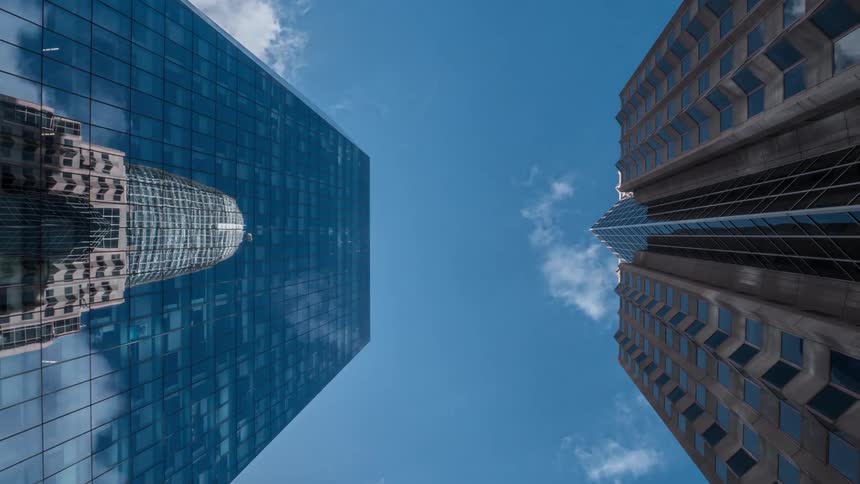 Two skyscraper buildings in front of each other with a cloudy sky on the background outdoors during day time