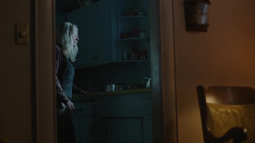 A woman walks over to a window looking out