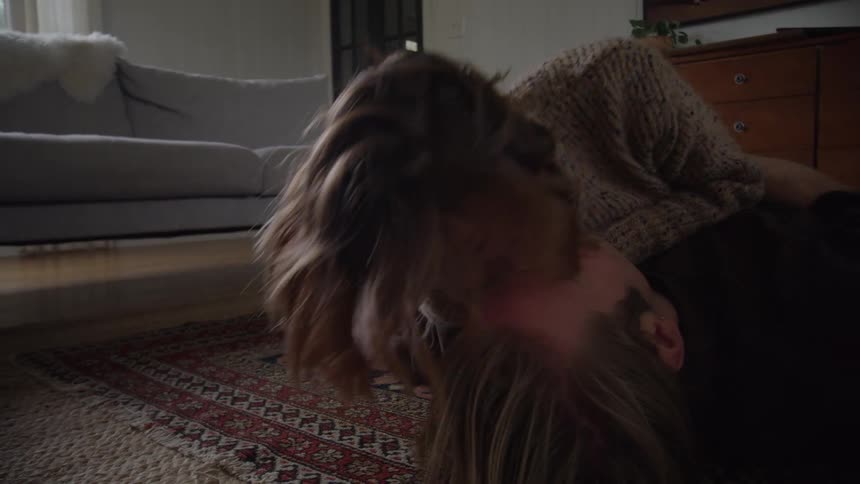 Couple kisses while lying on a rug in a softly lit room